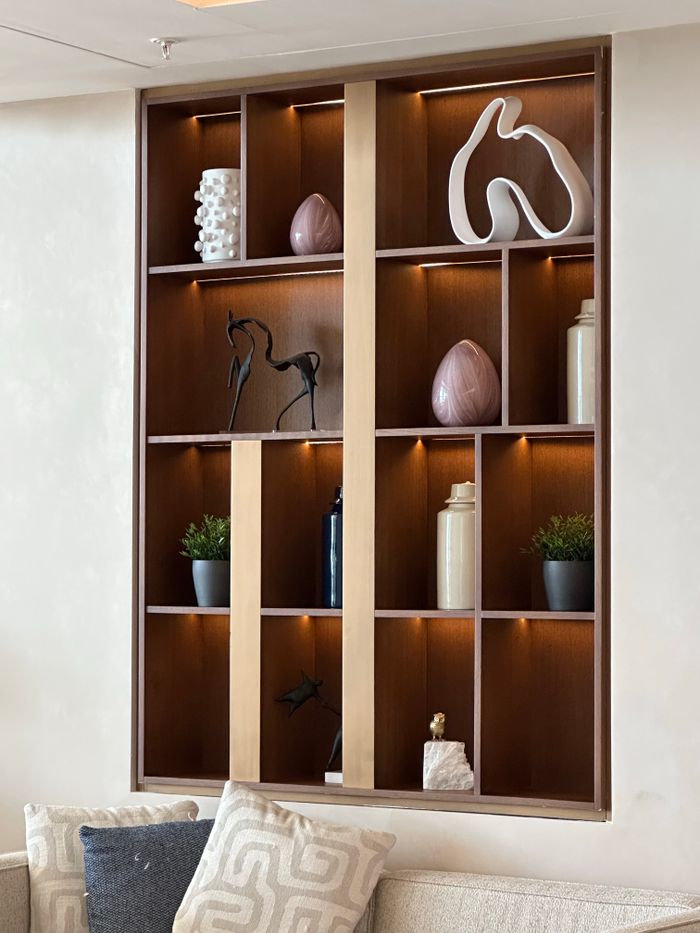 Stylish wooden wall shelf with decor items in a modern living room.