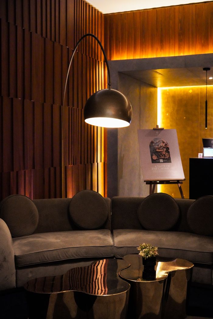 Warmly lit modern lounge with stylish curved sofa and standing lamp, ideal for relaxation.
